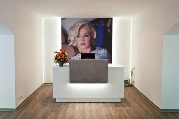 Moderner Empfangsbereich eines Friseursalons mit Blumen und großem Werbefoto.