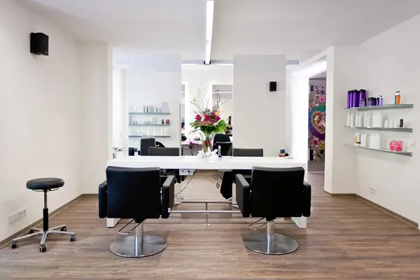 Moderner Friseursalon mit hellen Wänden, Spiegel, Stylingstühlen und Haarpflegeprodukten.