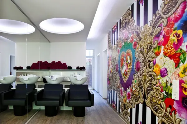 Moderner Friseursalon mit buntem Wandmuster, drei Waschplätzen und stilvoller Einrichtung.
